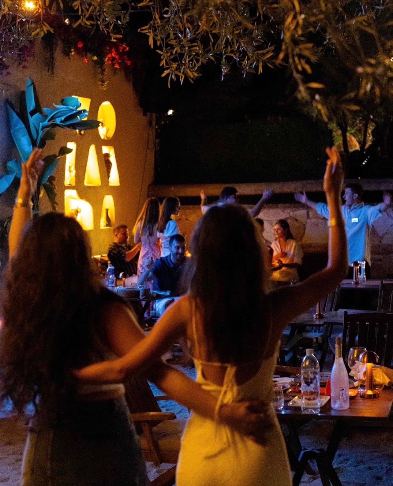 Junda Meyhane'nin hareketli terasında akşam kolları havada dans eden misafirler.